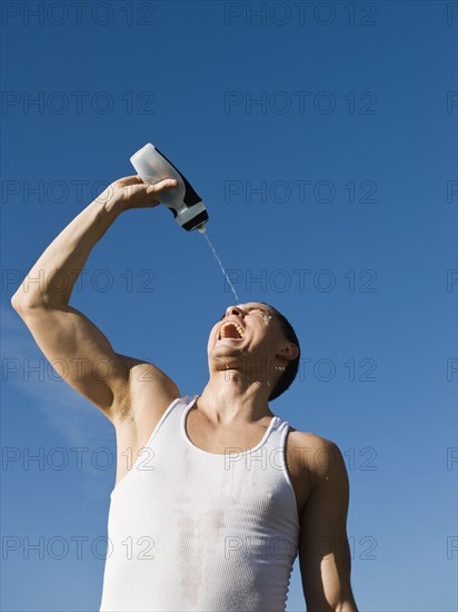 African man squirting water on his face