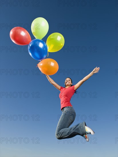 Native American holding balloons in mid-air