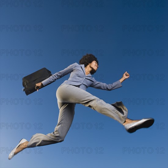African businesswoman carrying briefcase in mid-air