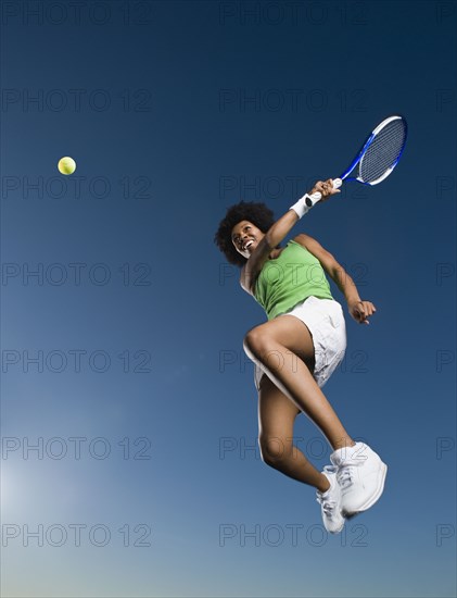 African woman playing tennis in mid-air