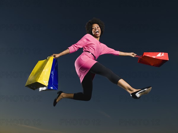 African woman holding shopping bags in mid-air