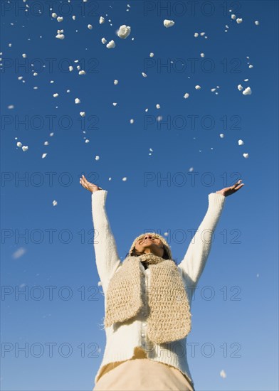 Mixed race woman throwing snow in air