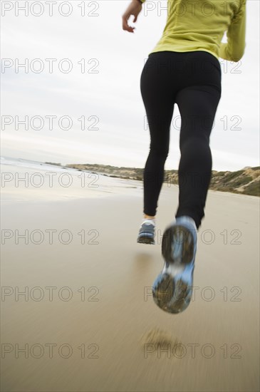 Hispanic woman running on beach