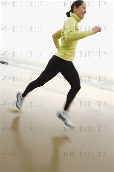 Hispanic woman running on beach