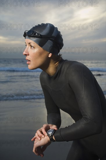 Hispanic woman in wetsuit on beach