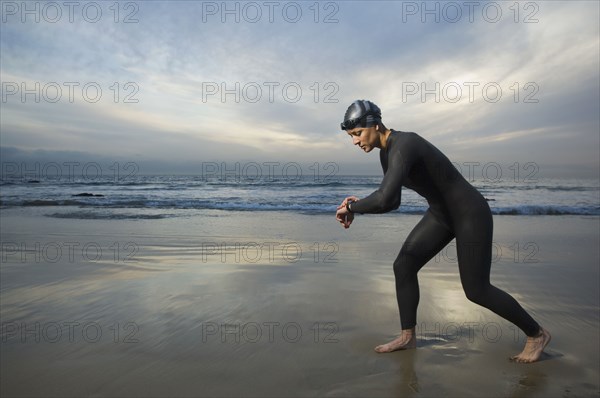 Hispanic woman in wetsuit on beach