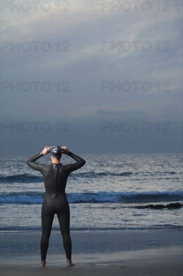 Hispanic woman in wetsuit on beach