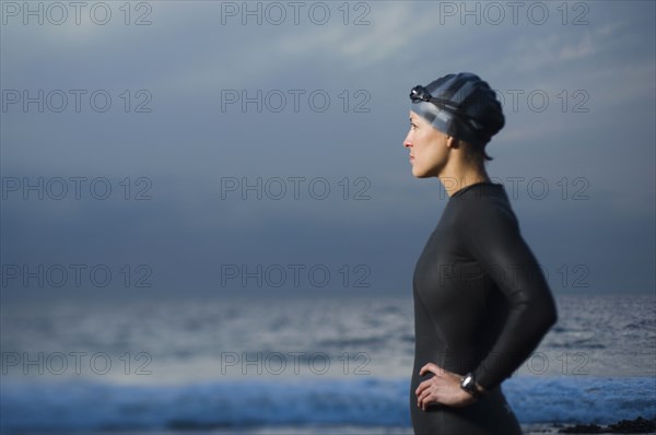 Hispanic woman in wetsuit on beach