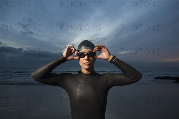 Hispanic woman in wetsuit on beach