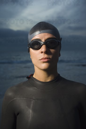 Hispanic woman in wetsuit on beach