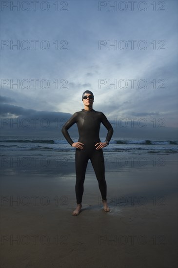 Hispanic woman in wetsuit on beach