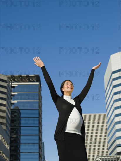 Pregnant Middle Eastern woman with arms raised outdoors