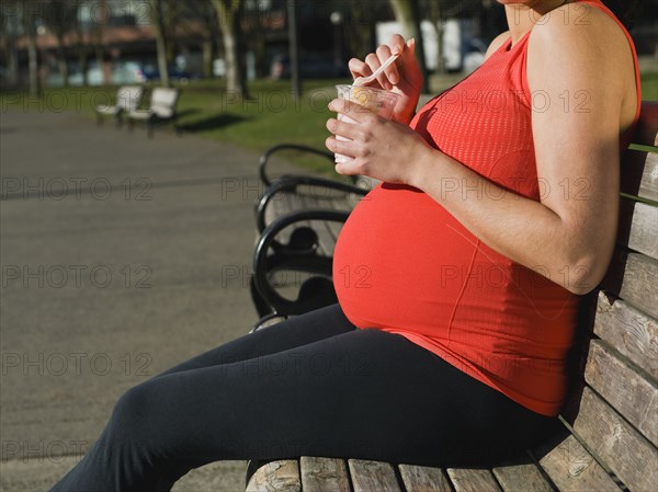 Pregnant Middle Eastern woman eating fruit in park