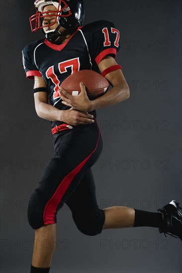 Mixed race football player holding football