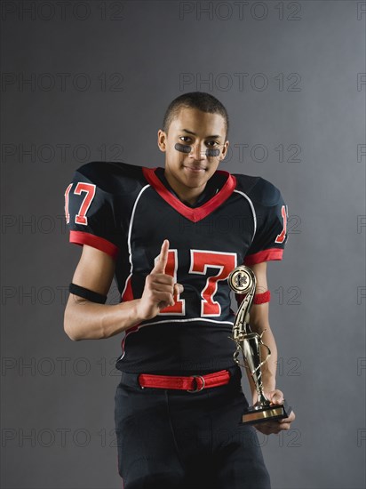 Mixed race football player holding trophy and gesturing
