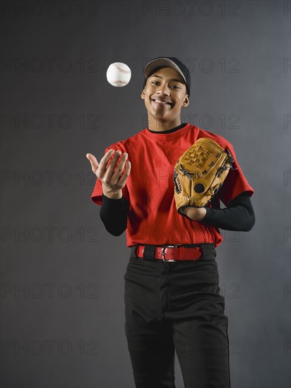 Mixed race baseball player tossing baseball