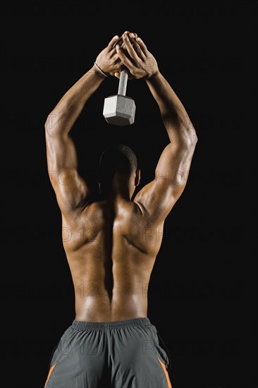 African man doing triceps extensions with dumbbell