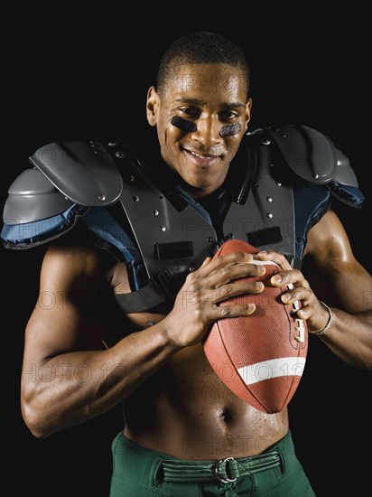 African football player holding football and wearing protective pads