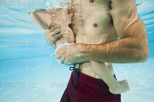 Mixed race father holding daughter in swimming pool