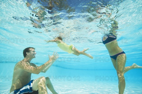 Parents swimming in swimming pool with daughter