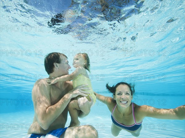 Parents swimming in swimming pool with daughter