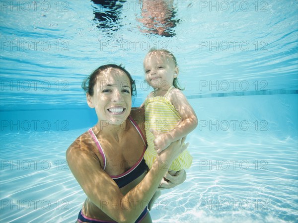 Mother underwater in swimming pool with daughter