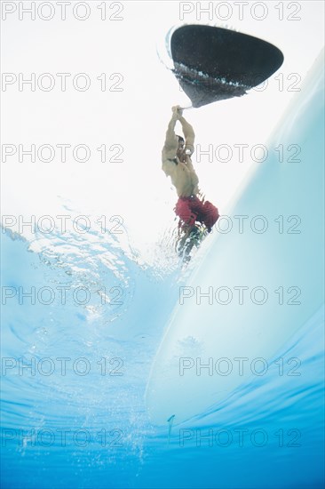 Mixed race man paddling on surfboard