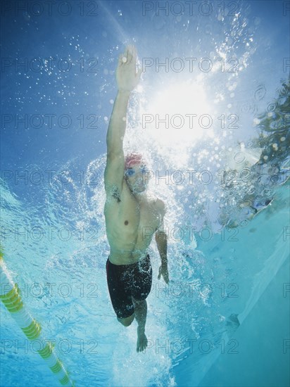 Mixed race man swimming in swimming pool