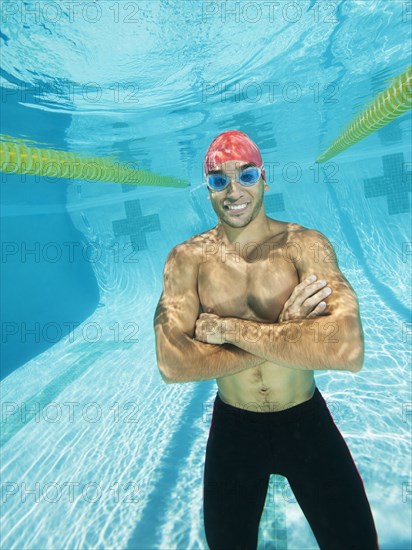 Mixed race man standing underwater in swimming pool