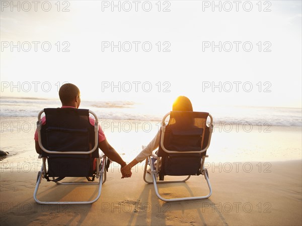 Couple holding hands on beach at sunset