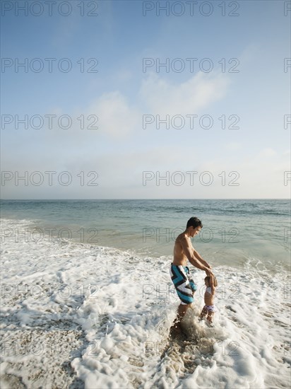 Mixed race father and daughter playing in ocean together