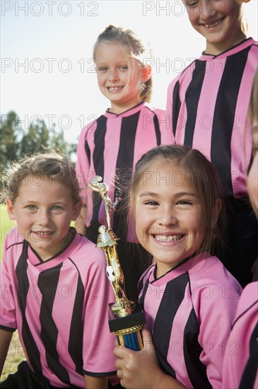 Smiling girl soccer players posing with trophy