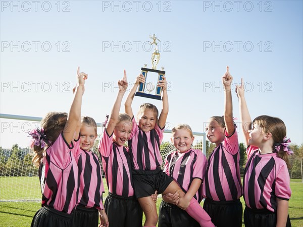 Cheering girl soccer players posing with trophy