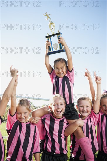 Cheering girl soccer players posing with trophy