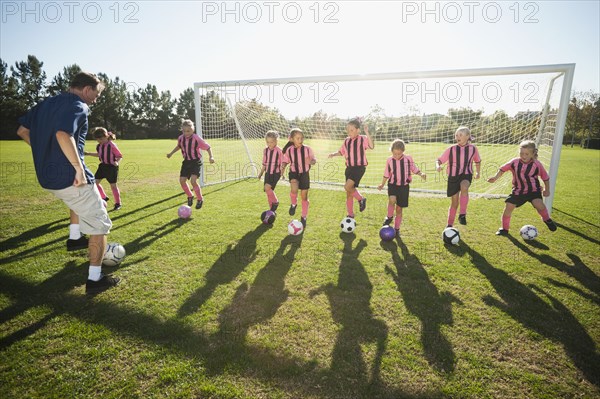 Coach practicing with girl soccer players