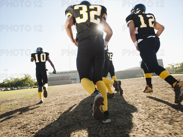 Football players running on football field