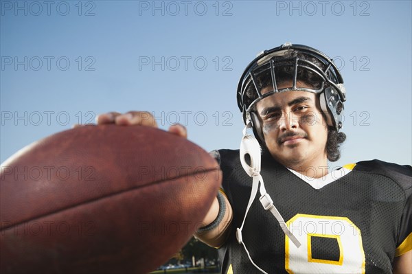 Hispanic football player holding football