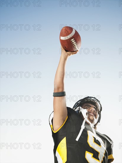 Hispanic football player lifting football