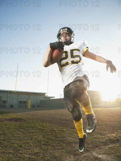 Hispanic football player running with football