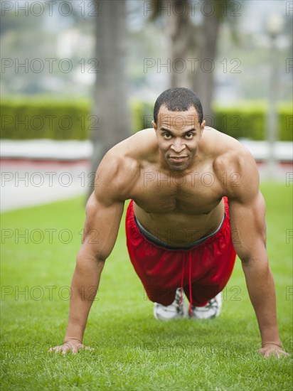 Mixed race man doing push-ups in park