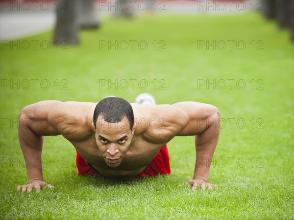 Mixed race man doing push-ups in park