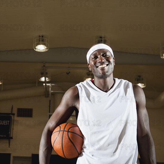 Black man holding basketball on basketball court