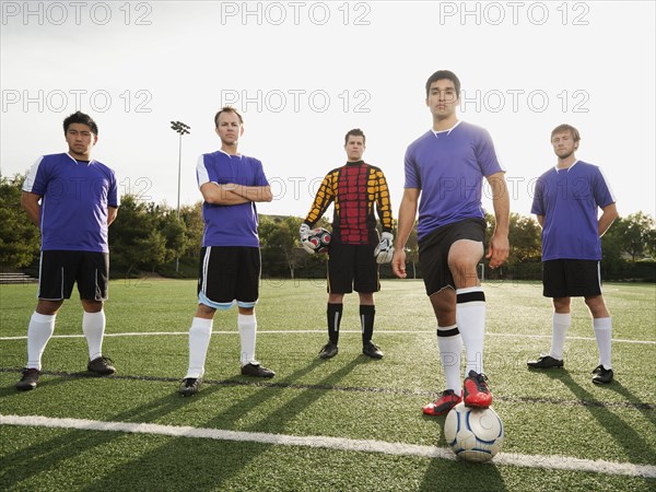 Men standing with ball on soccer field