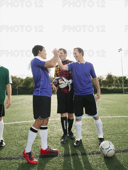 Soccer players cheering on soccer field