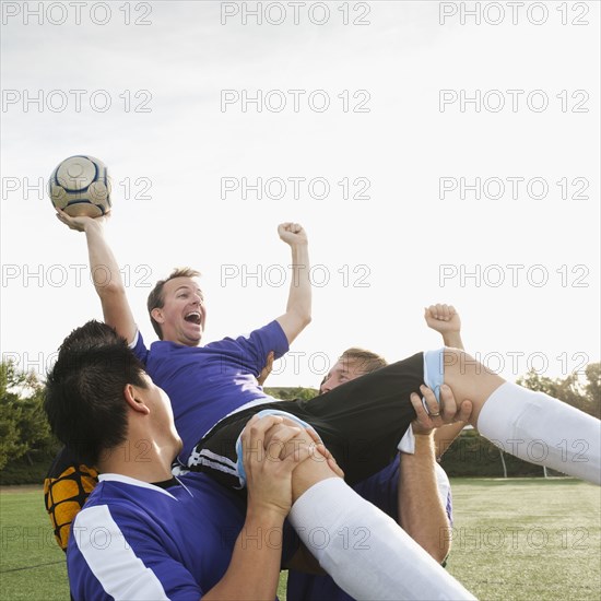 Soccer players lifting teammate and cheering