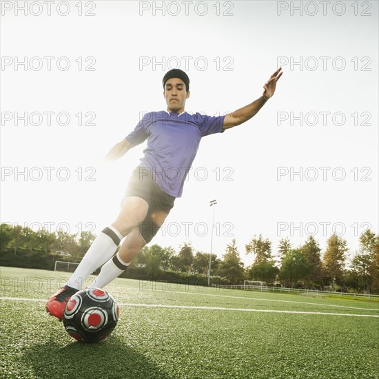 Mixed race soccer player kicking soccer ball