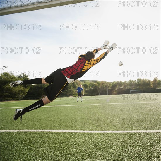 Mixed race goalkeeper in mid-air protecting goal