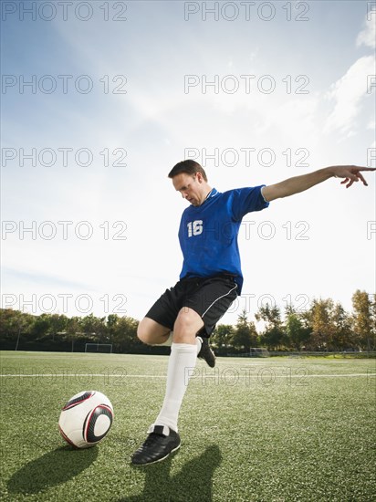 Caucasian soccer player kicking soccer ball