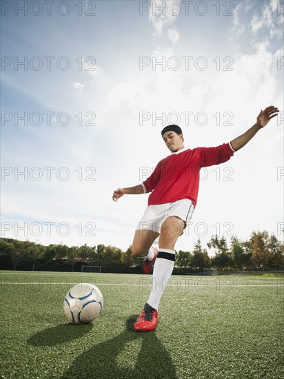 Mixed race soccer player kicking soccer ball