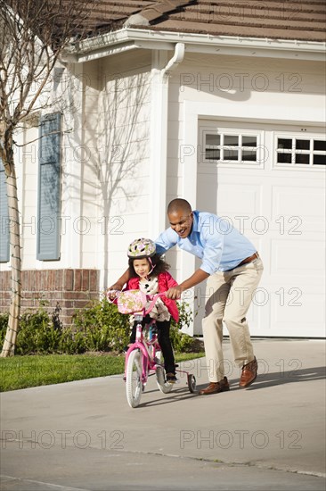 Father helping daughter learn to ride a bike